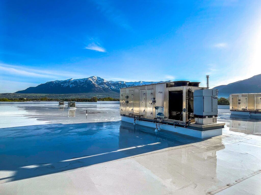 a heating and air unit on the roof of a building near mountains