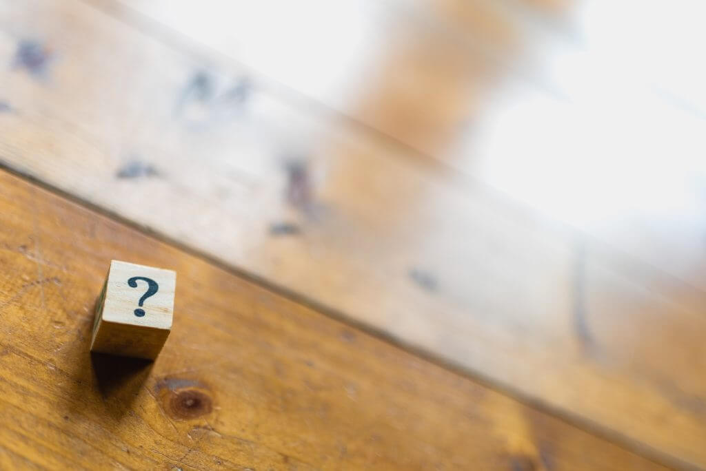 Wooden dice with question mark and doubt.